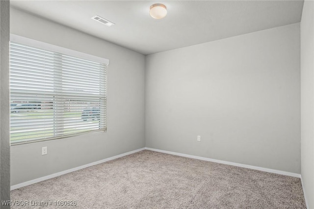 carpeted spare room with visible vents and baseboards