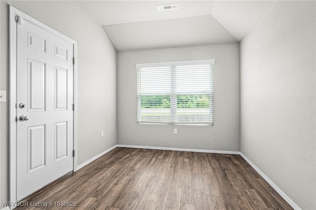 empty room featuring visible vents, baseboards, lofted ceiling, and wood finished floors