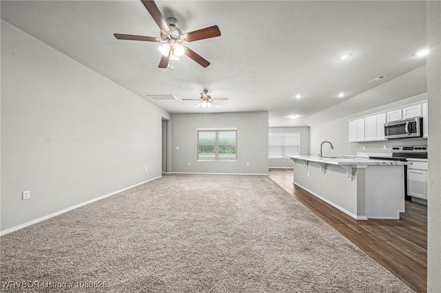 kitchen featuring ceiling fan, a kitchen island with sink, a sink, a breakfast bar, and stainless steel appliances