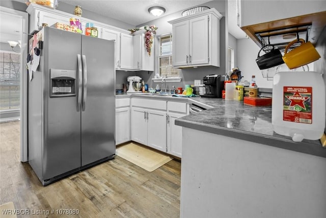 kitchen featuring stainless steel fridge, a healthy amount of sunlight, sink, white cabinets, and light hardwood / wood-style floors