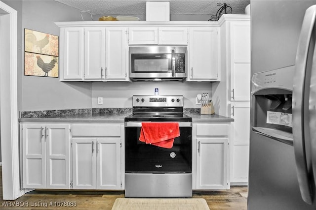 kitchen featuring appliances with stainless steel finishes, a textured ceiling, white cabinetry, and wood-type flooring