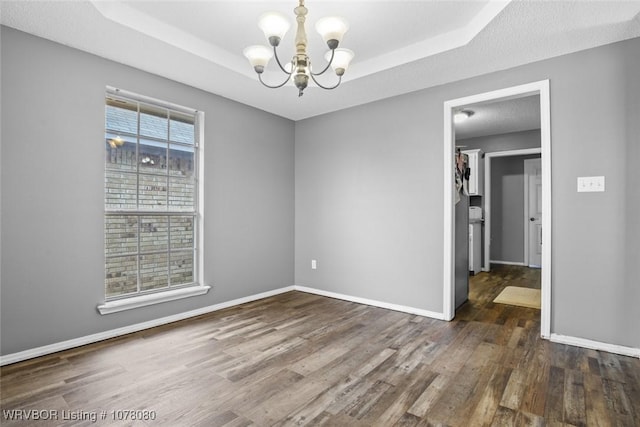 spare room with a healthy amount of sunlight, a raised ceiling, and an inviting chandelier