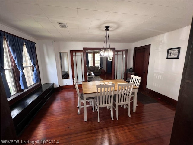 dining space featuring dark hardwood / wood-style flooring and an inviting chandelier