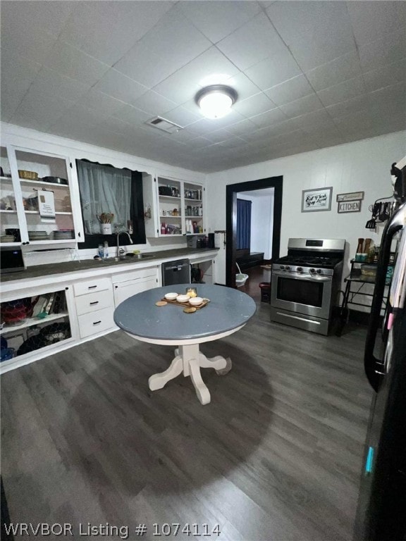 kitchen with white cabinetry, sink, stainless steel gas range oven, built in features, and dark hardwood / wood-style floors