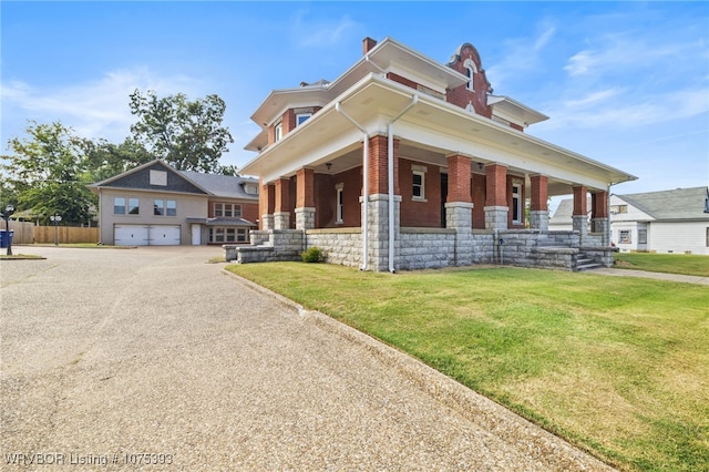 view of front of home featuring covered porch, a garage, and a front yard