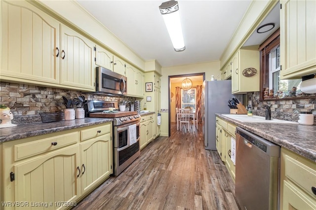 kitchen featuring sink, stainless steel appliances, tasteful backsplash, hardwood / wood-style floors, and cream cabinetry