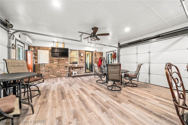 dining space with a wall mounted AC, ceiling fan, light hardwood / wood-style floors, and brick wall