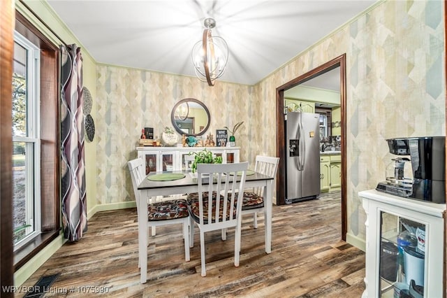 dining room featuring crown molding, hardwood / wood-style floors, a healthy amount of sunlight, and a notable chandelier