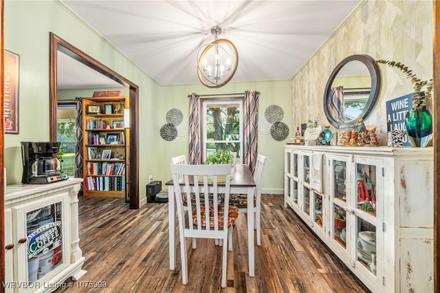 dining space with dark wood-type flooring, a chandelier, and ornamental molding