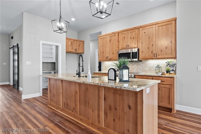 2006 Yellowstone Dr, Barling, AR 72923 - kitchen with pendant lighting, a kitchen island with sink, light stone counters, dark hardwood / wood-style flooring, and a chandelier