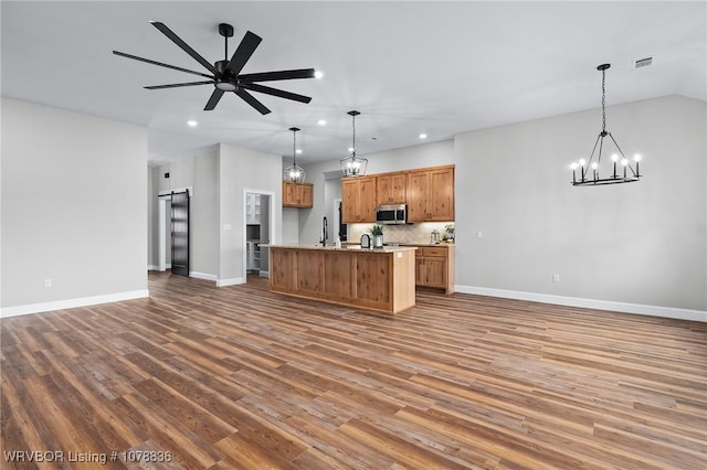 2006 Yellowstone Dr, Barling, AR 72923 - kitchen with hardwood / wood-style flooring, ceiling fan with notable chandelier, an island with sink, decorative light fixtures, and a barn door