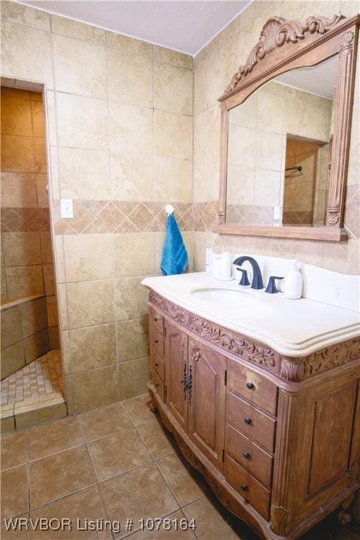 bathroom featuring tile patterned flooring, vanity, tile walls, and walk in shower