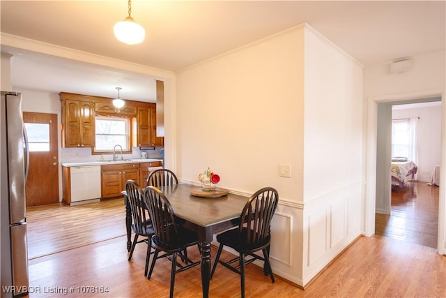 dining area with light hardwood / wood-style floors, plenty of natural light, crown molding, and sink