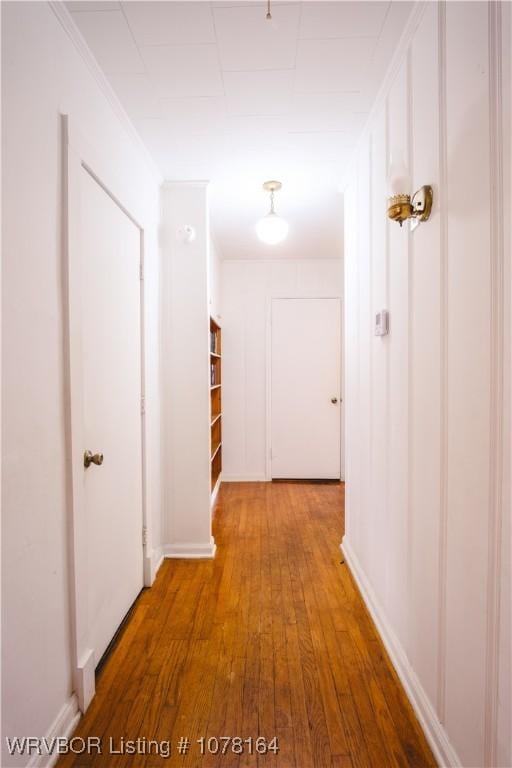 hallway featuring wood-type flooring and ornamental molding