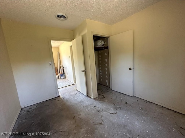 unfurnished bedroom featuring a textured ceiling and a closet