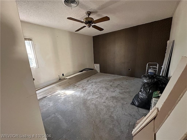 unfurnished room with ceiling fan and a textured ceiling