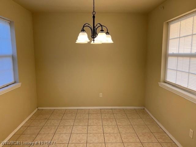 tiled empty room with a chandelier