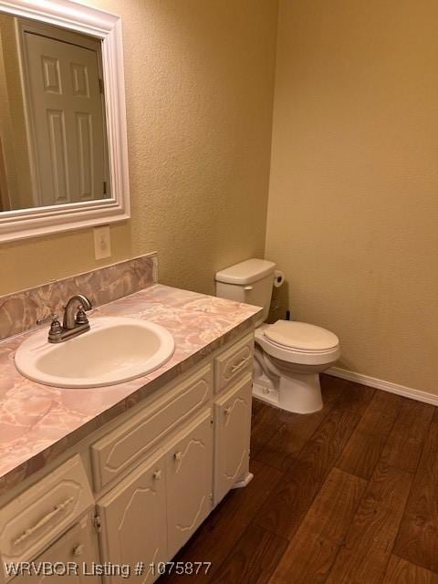 bathroom with hardwood / wood-style floors, vanity, and toilet