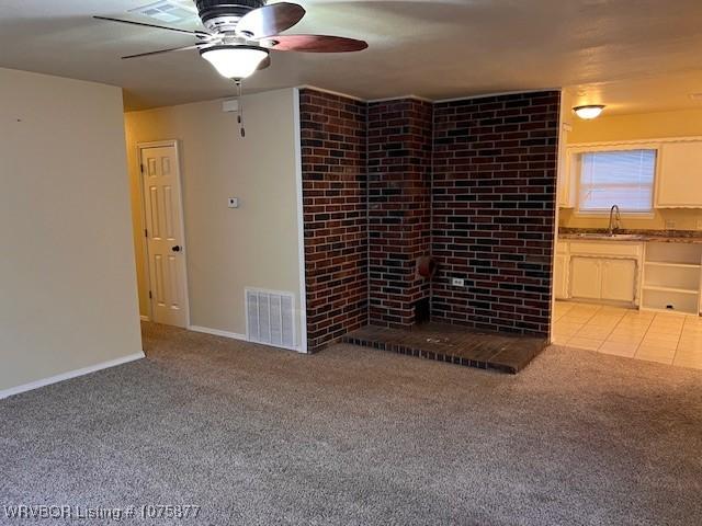 unfurnished living room with a fireplace, light colored carpet, and ceiling fan