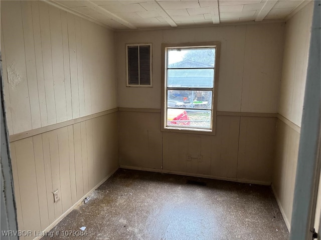 unfurnished room with wood walls, wainscoting, and visible vents