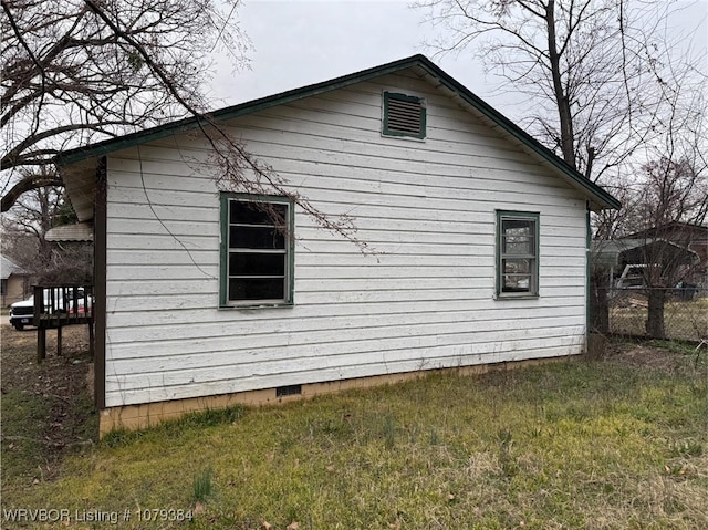 view of side of property with crawl space and fence