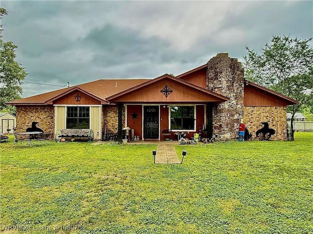 ranch-style house featuring a shed, a front yard, a chimney, and covered porch