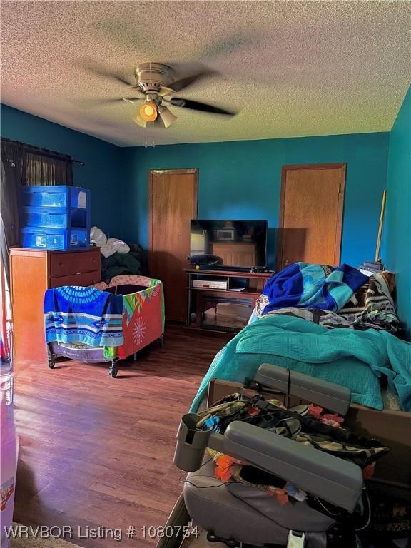 bedroom with a ceiling fan, a textured ceiling, and wood finished floors