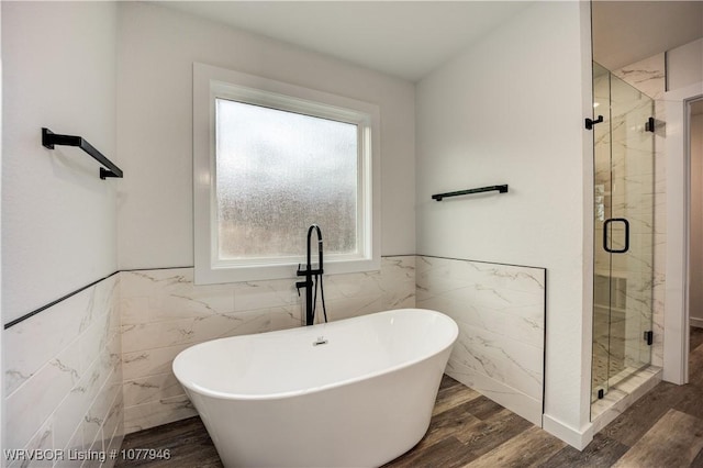 bathroom featuring hardwood / wood-style flooring, separate shower and tub, and tile walls