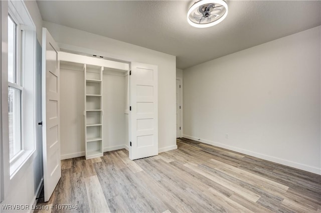 unfurnished bedroom featuring a textured ceiling, light hardwood / wood-style flooring, and a closet