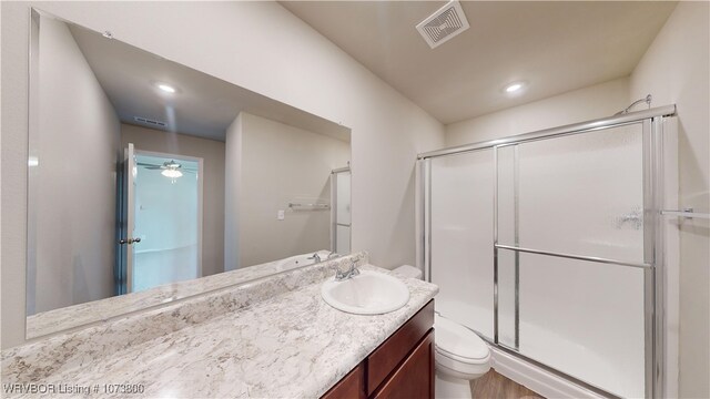 bathroom with vanity, toilet, an enclosed shower, and ceiling fan