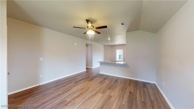 interior space with hardwood / wood-style floors, ceiling fan, sink, and vaulted ceiling