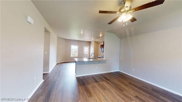 unfurnished living room with ceiling fan, dark hardwood / wood-style flooring, sink, and vaulted ceiling