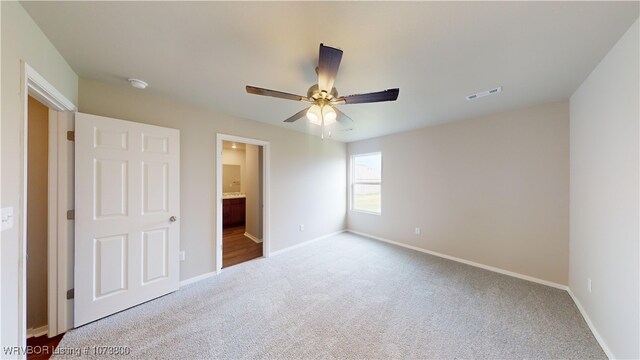 unfurnished bedroom with carpet flooring, ceiling fan, and ensuite bath