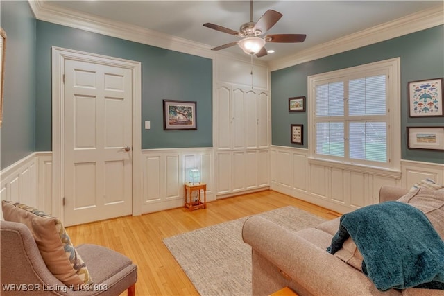 1232 Elizabeth Ln, Fort Smith, AR 72903 - living room featuring crown molding, a ceiling fan, light wood-style flooring, a wainscoted wall, and a decorative wall
