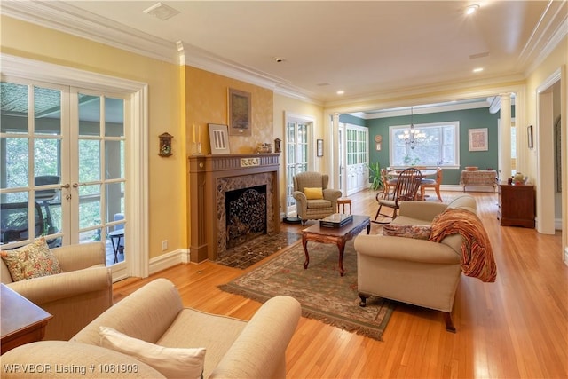 1232 Elizabeth Ln, Fort Smith, AR 72903 - living room featuring light wood finished floors, ornamental molding, a chandelier, a fireplace, and french doors