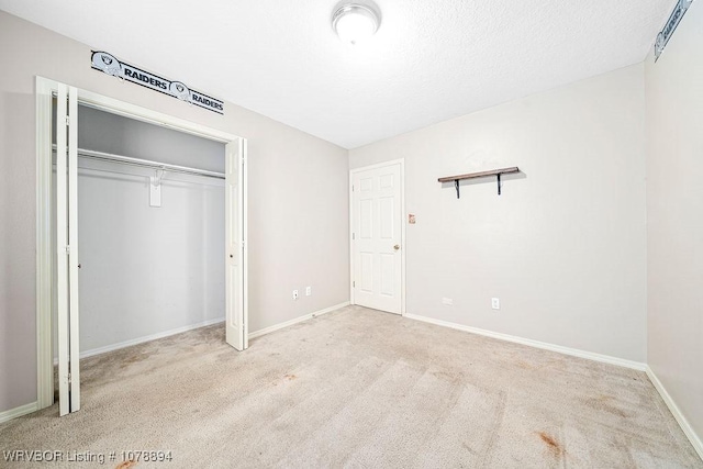 unfurnished bedroom with light colored carpet, a textured ceiling, and a closet