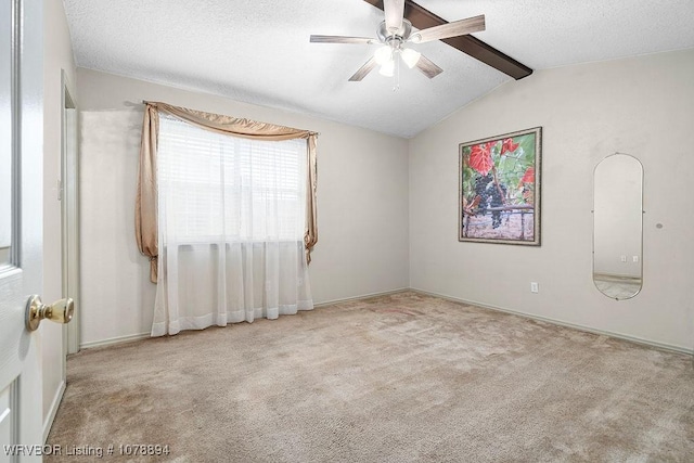 empty room with ceiling fan, a textured ceiling, light carpet, and vaulted ceiling with beams