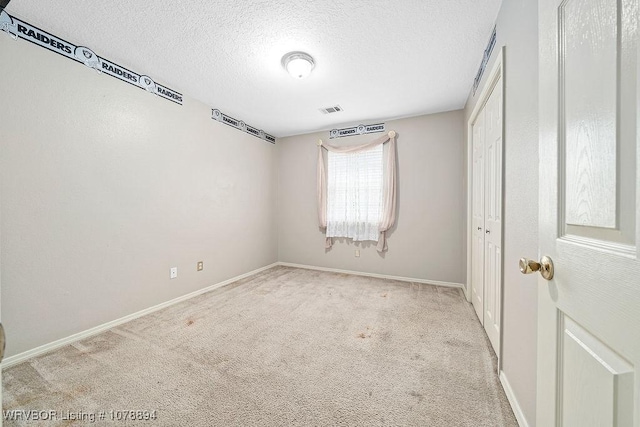 empty room with light carpet and a textured ceiling