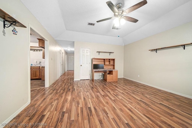 unfurnished living room featuring sink, ceiling fan, dark hardwood / wood-style floors, a tray ceiling, and vaulted ceiling