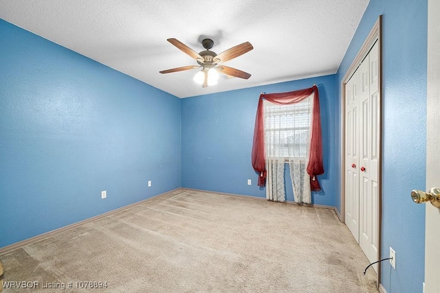 spare room with ceiling fan, light colored carpet, and a textured ceiling