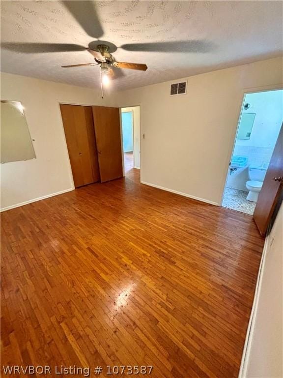 empty room with hardwood / wood-style flooring, ceiling fan, and a textured ceiling