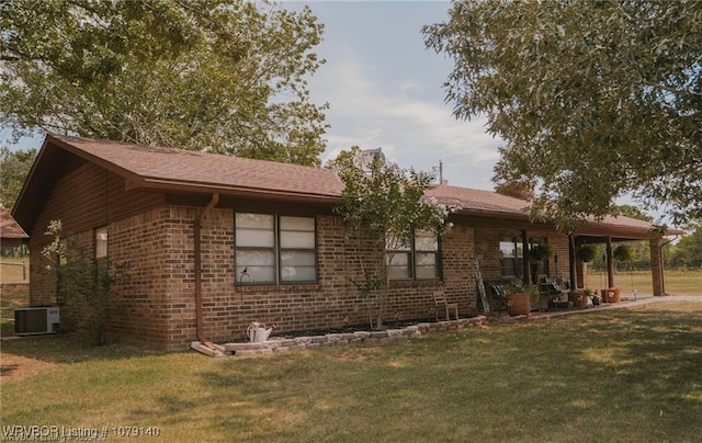 ranch-style home featuring a front lawn, cooling unit, and brick siding