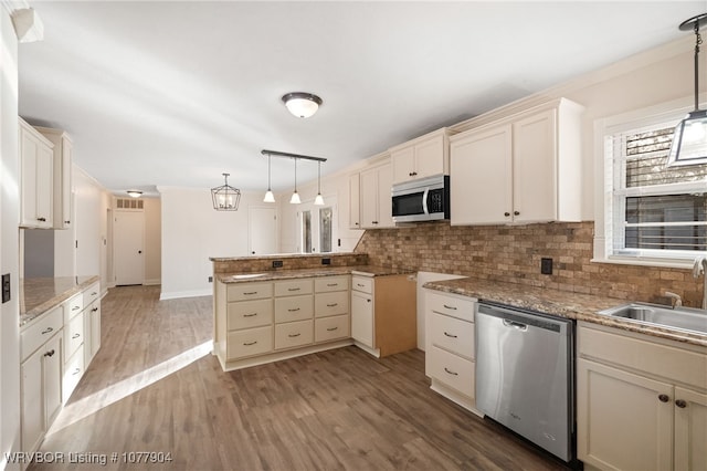 kitchen featuring light hardwood / wood-style floors, sink, hanging light fixtures, and appliances with stainless steel finishes