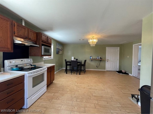 kitchen with white electric stove, under cabinet range hood, light countertops, light wood-type flooring, and stainless steel microwave