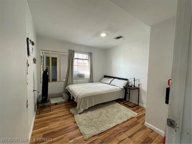 bedroom featuring light wood-type flooring, baseboards, and visible vents