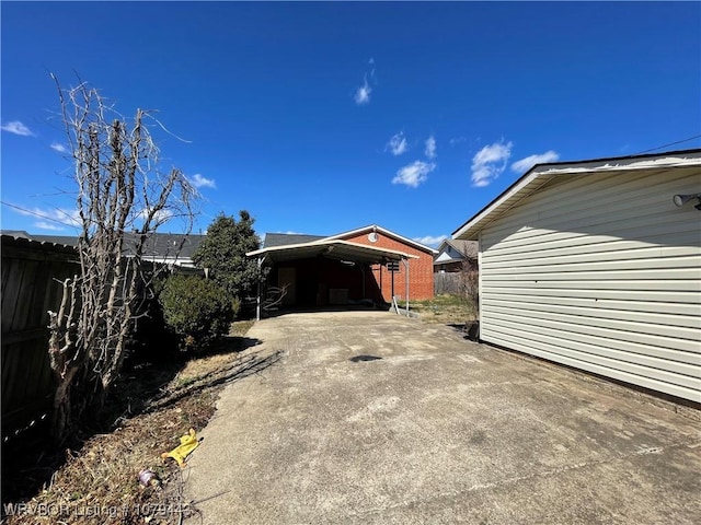 view of property exterior featuring concrete driveway, a carport, and fence