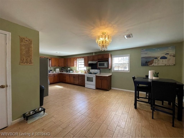 kitchen with light wood finished floors, appliances with stainless steel finishes, and light countertops