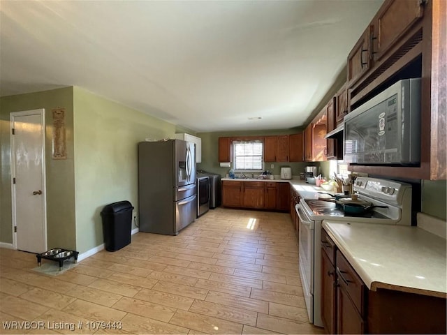 kitchen featuring stainless steel appliances, light countertops, light wood-style floors, and separate washer and dryer