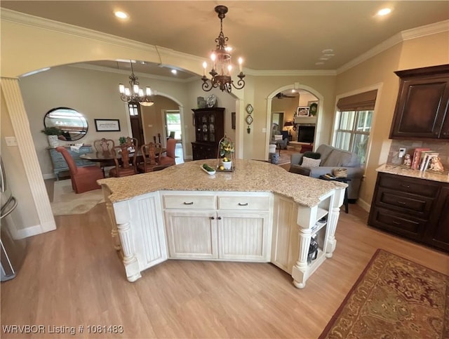 3414 Bugscuffle Rd, Lavaca, AR 72941 - kitchen with arched walkways, light wood-style flooring, dark brown cabinets, ornamental molding, and a chandelier