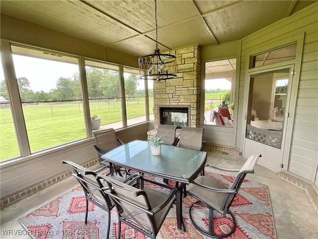 3414 Bugscuffle Rd, Lavaca, AR 72941 - sunroom / solarium with a chandelier, unfinished concrete flooring, an outdoor stone fireplace, and outdoor dining space